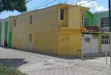 Se observa la fachada del club de tareas, es amarilla y la estructura se ve vieja